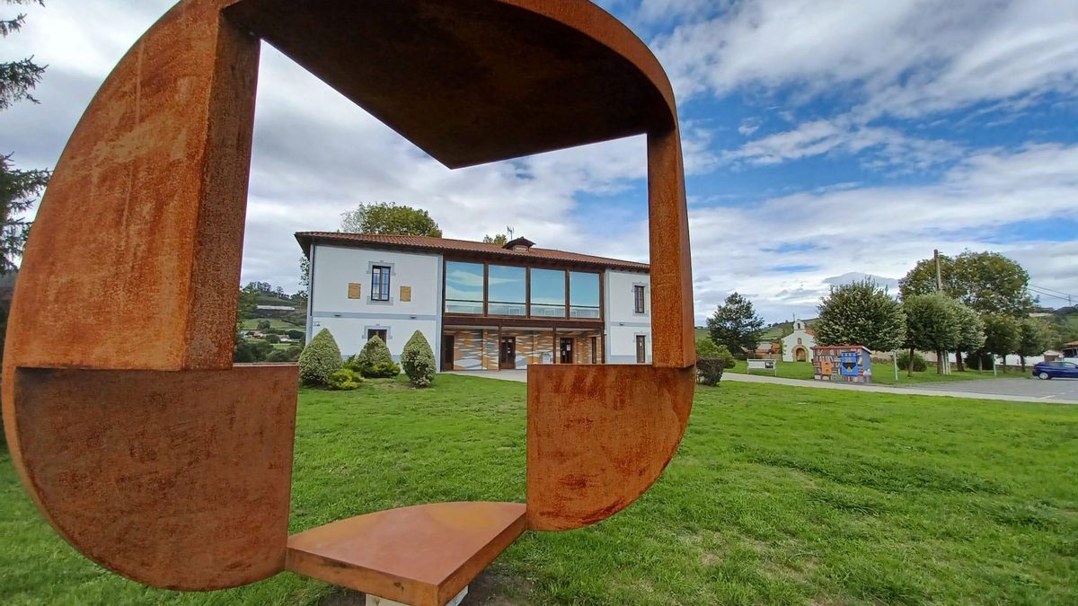 La Casa de los Alonso del Campo, vista a través de la escultura de Benjamín Menéndez, con la capilla tambiém al fondo de la imagen, a la derecha.