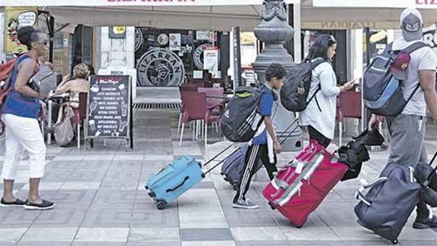 Turistas, con sus maletas por la Plaça Major, ayer: el centro de Palma aglutina la mayor parte de la oferta ilegal de turismo en pisos.