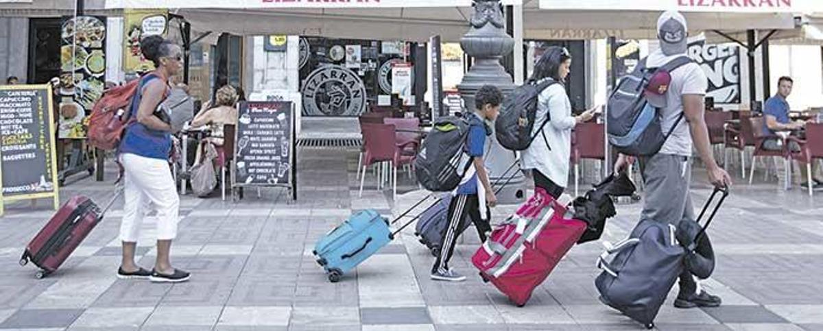 Turistas, con sus maletas por la Plaça Major, ayer: el centro de Palma aglutina la mayor parte de la oferta ilegal de turismo en pisos.
