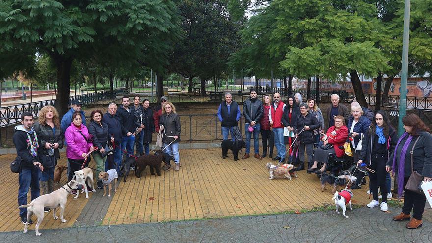 Propietarios de perros, ayer en el Parque de María Luisa, con el espacio para sus mascotas detrás.