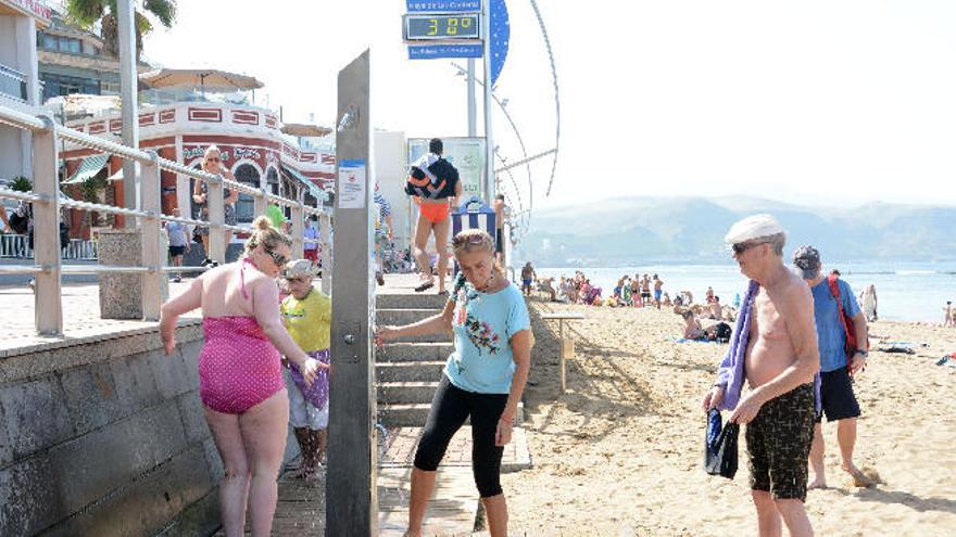 Varios bañistas en una de las duchas de la playa de Las Canteras, ayer, con el termómetro a 30 grados.