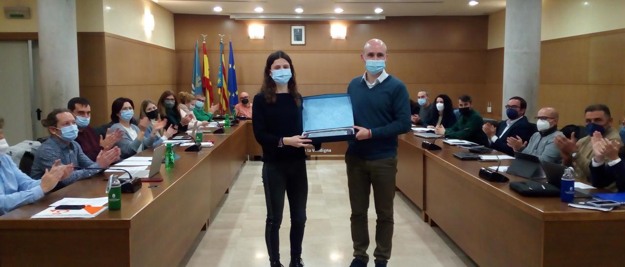 Mara Rolli Grau recibe de manos del alcalde la placa de reconocimiento ante los aplausos de la corporación municipal