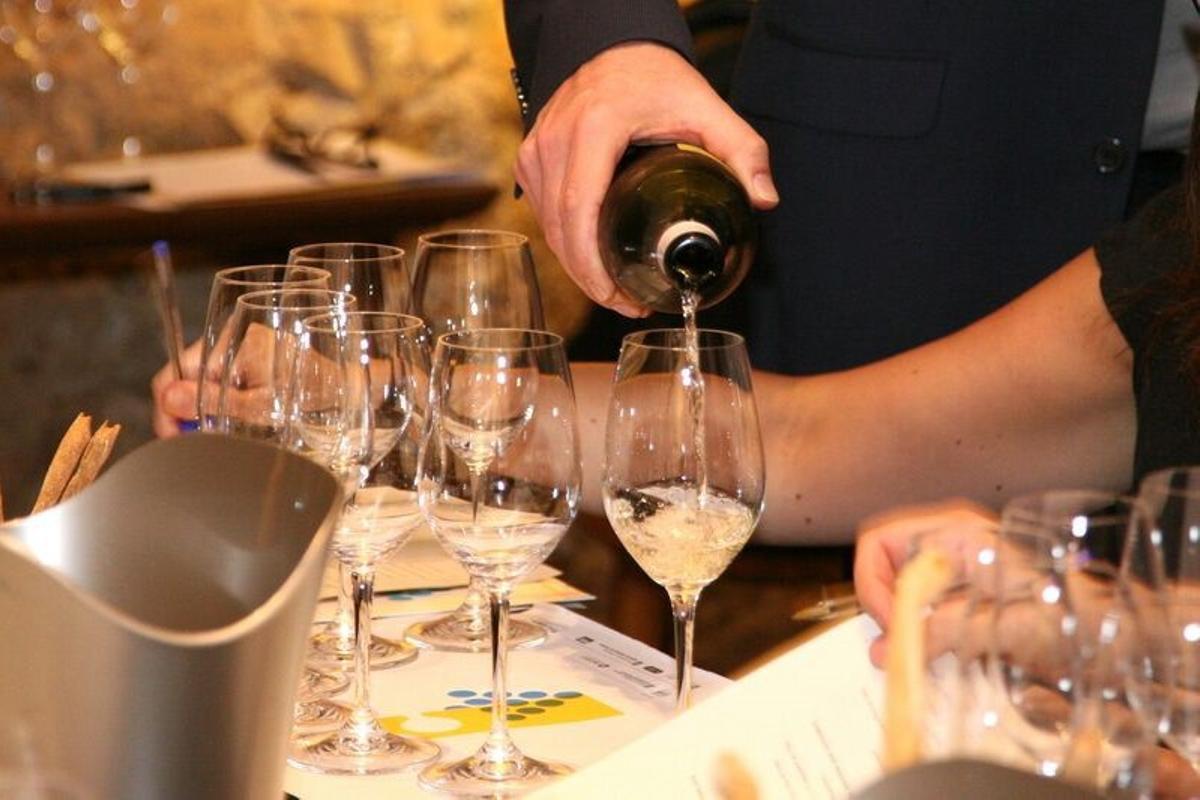 Un camarero sirve una copa de vino blanco de una de las denominaciones de origen (DO) catalanas.