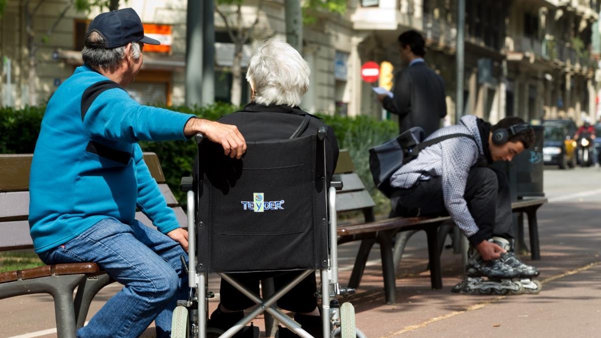 Una persona dependiente y su acompañante, en el paseo de Sant Joan