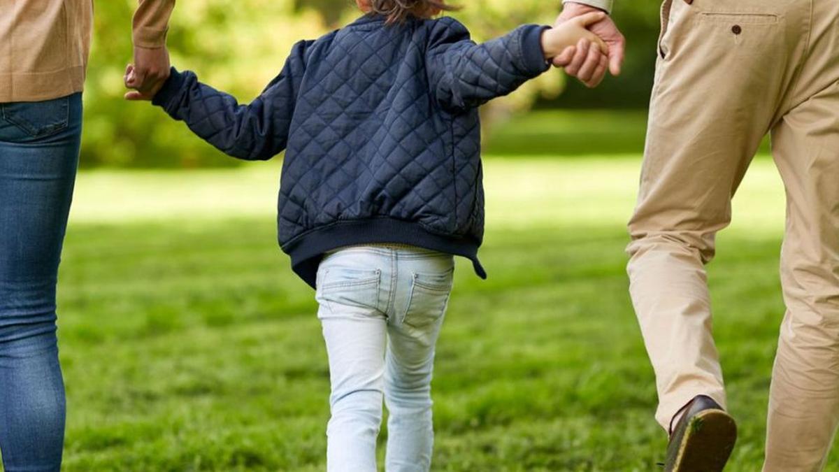 Foto de archivo de una pareja paseando con su hija menor de edad.