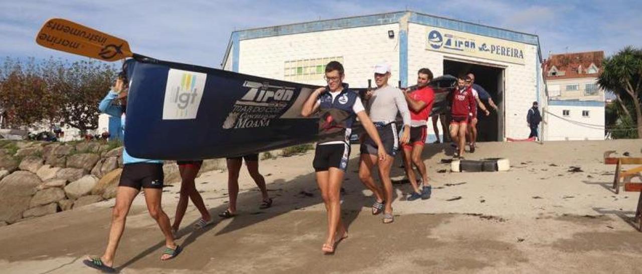 Remeros de la SD Tirán portan la trainera hacia el agua para su primer entrenamiento. |  // FDV