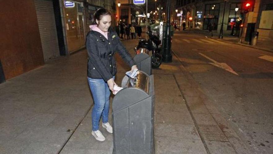 Una joven deposita basura en uno de los contenedores de la calle Uruguay.  // Marta G. Brea