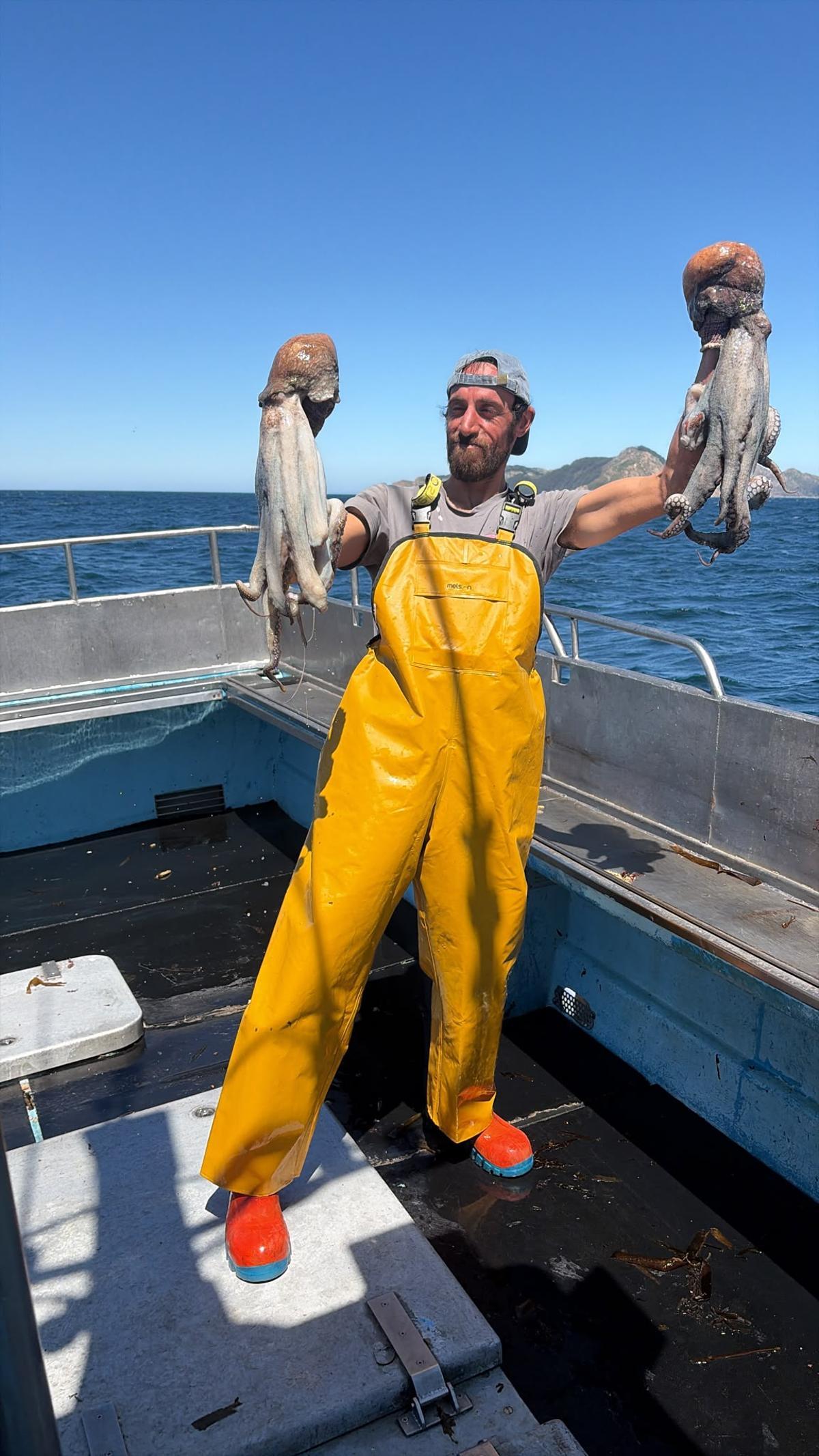 Un marinero de la flota de Cangas con dos pulpos en sus manos.