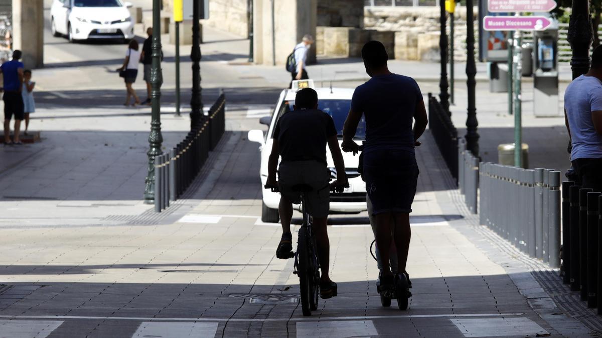 Un ciclista y un usuario de patinetes circulando en dirección contraria por la calle Don Jaime.