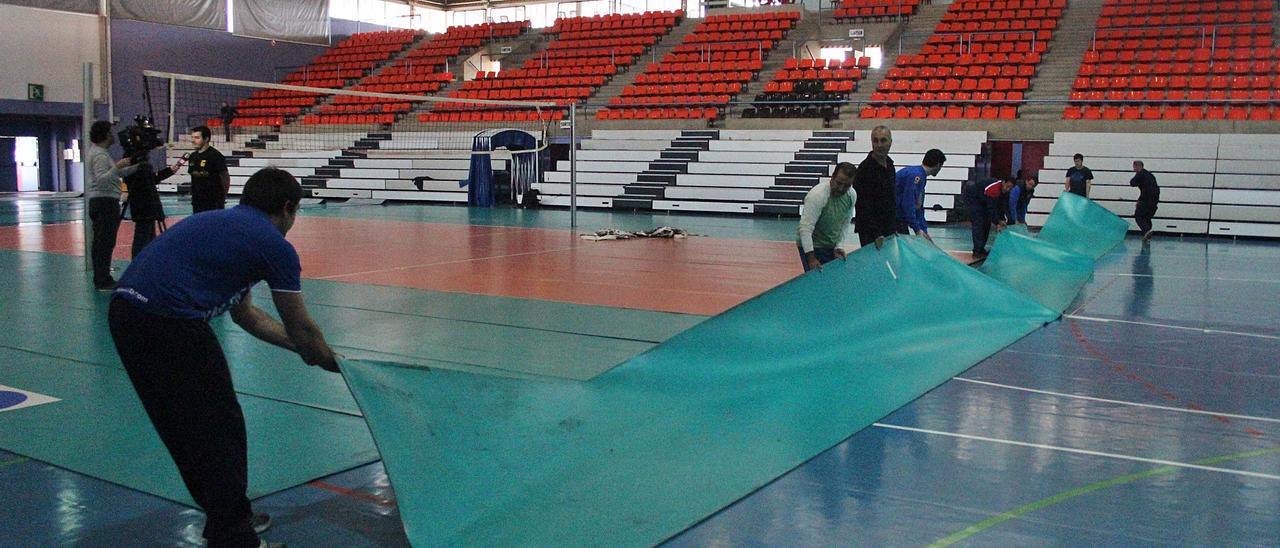 Un grupo de operarios instalan sobre la pista del pabellón de sa Blanca Dona un recubrimiento sintético para la celebración de un evento deportivo.