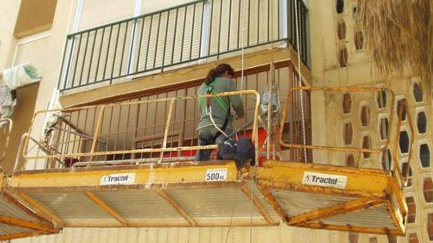 Un operario trabaja en la fachada de un edificio.