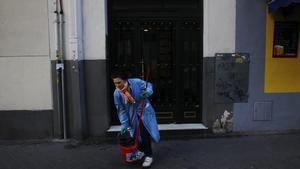 Una trabajadora del hogar termina de limpiar fuera de su edificio, en Madrid.