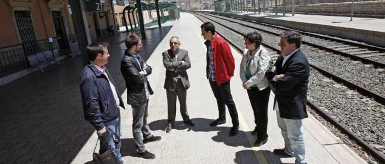 Un tren pasa de largo por Novelda y abajo los dirigentes del PSOE en la estación de Elda.