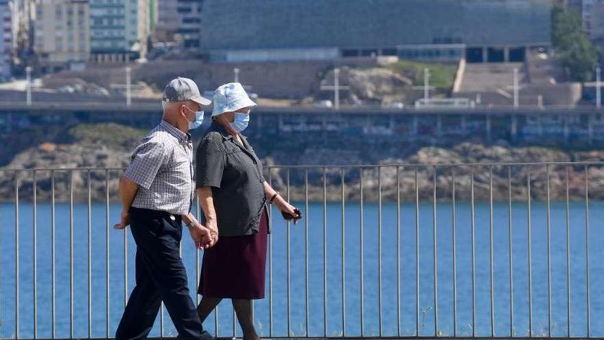 Un hombre y una mujer con mascarilla pasean por Riazor.