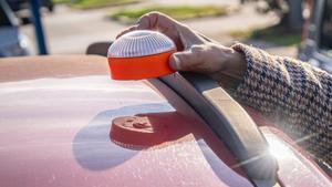 Una mujer coloca una baliza V16 en el capó de su coche.