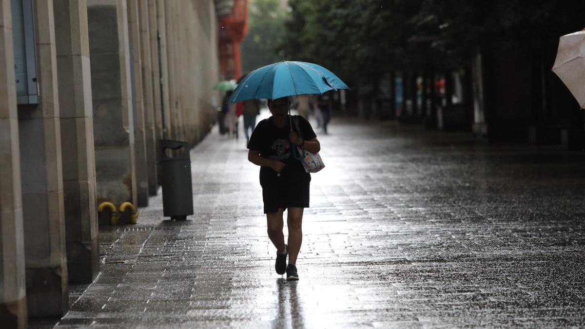 Una mujer camina bajo la lluvia en Zaragoza