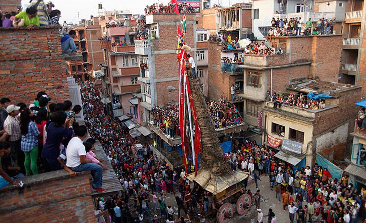 Un sacerdot llança aquest diumenge un coco des del carro del déu Minath, durant el festival de carros de Rato Machhindranath, a la ciutat nepalesa de Lalitpur.