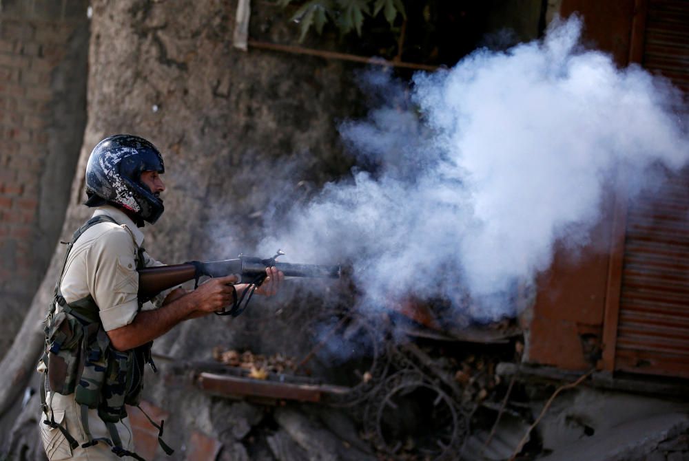 An Indian policeman fires a teargas shell ...