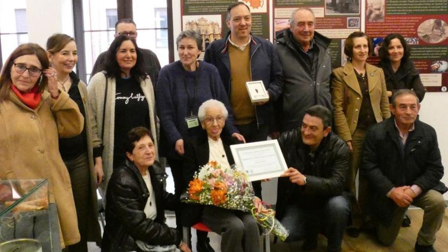 Alejandro Vega, de pie, en el centro, con la distinción, y Marina Morís, sentada con un ramo de flores, acompañados de familiares e integrantes de la entidad azabachera maliayesa. | V. A.