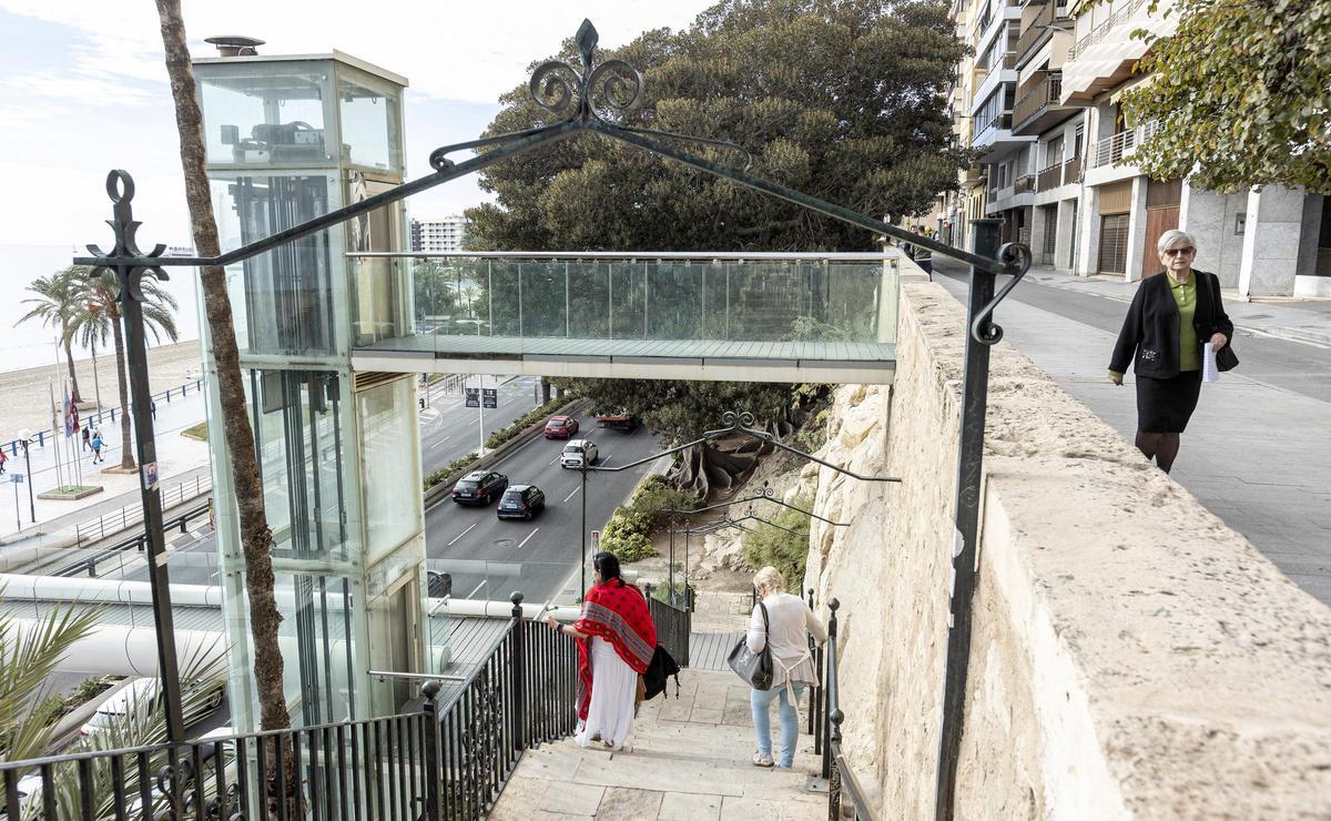 Dos personas bajan por las escaleras junto al ascensor averiado.