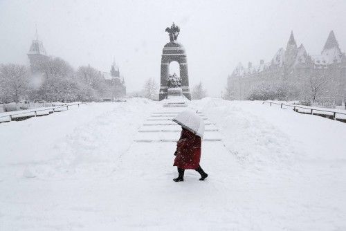 Una mujer camina frente al Monumento de la Guerra Nacional en Ottawa
