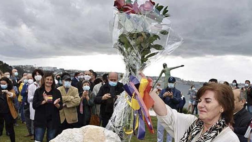 Olga Manzanero, onte en Bastiagueiriño, con 13 rosas na man, xunto á placa e detrás a escultura.