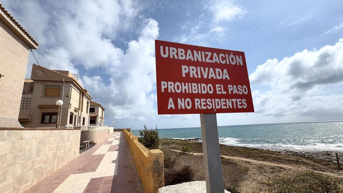 Cartel que prohibe el paso a los peatones junto al mar en un residencial de La Torre del Moro de Torrevieja