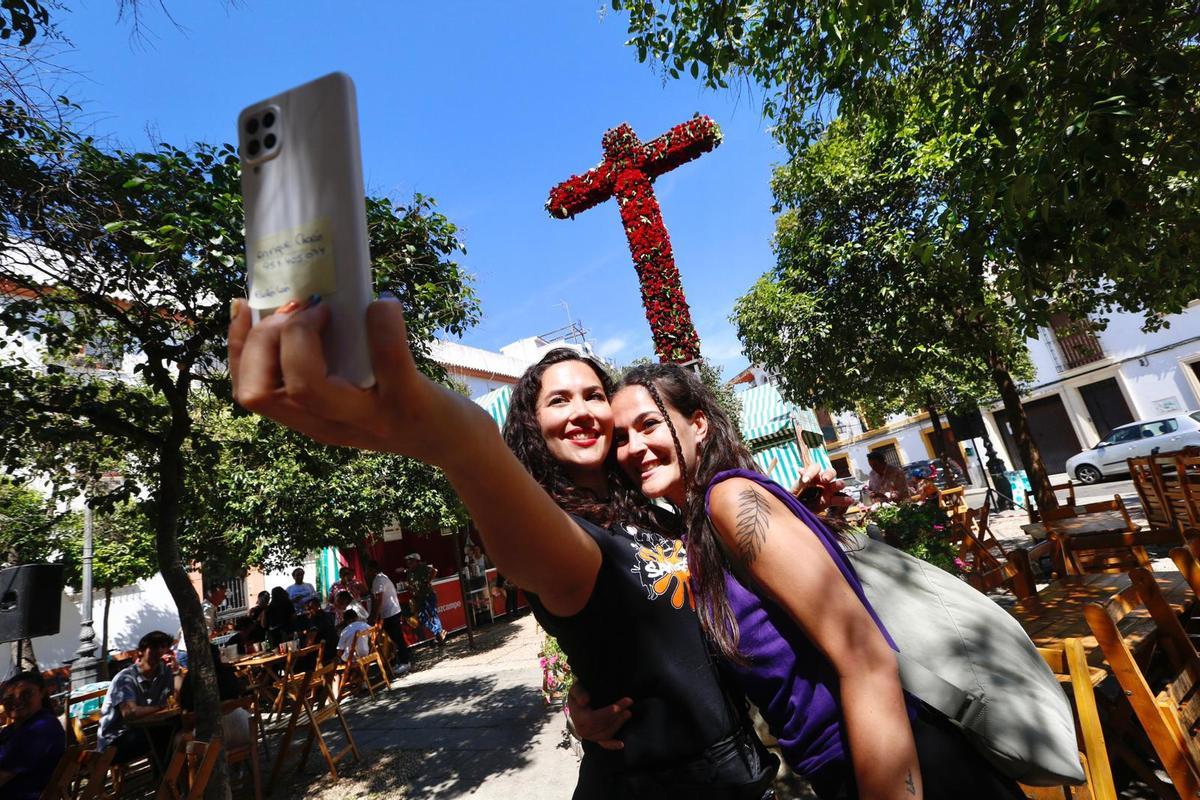 Dos chicas se hacen una foto en una cruz de mayo, este lunes, en Córdoba.