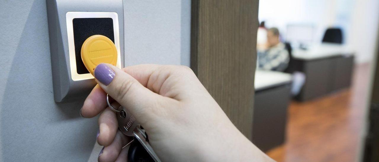 Una empleada utiliza una llave digital para fichar al comenzar y terminar su jornada laboral en unas oficinas.