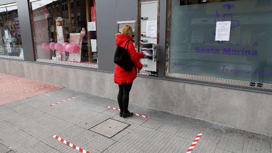 Una mujer accede a la taquilla inteligente instalada en la farmacia de Santa Marina.