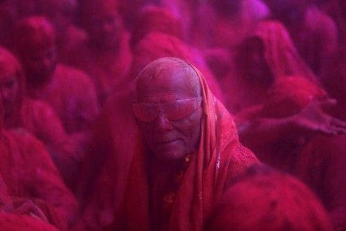 A Hindu devotee looks on in a cloud of coloured powder inside a temple during "Lathmar Holi" at the village of Barsana