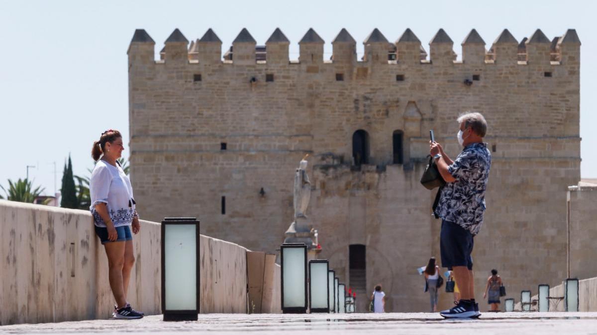 Dos turistas se fotografían en el Puente Romano de Córdoba.