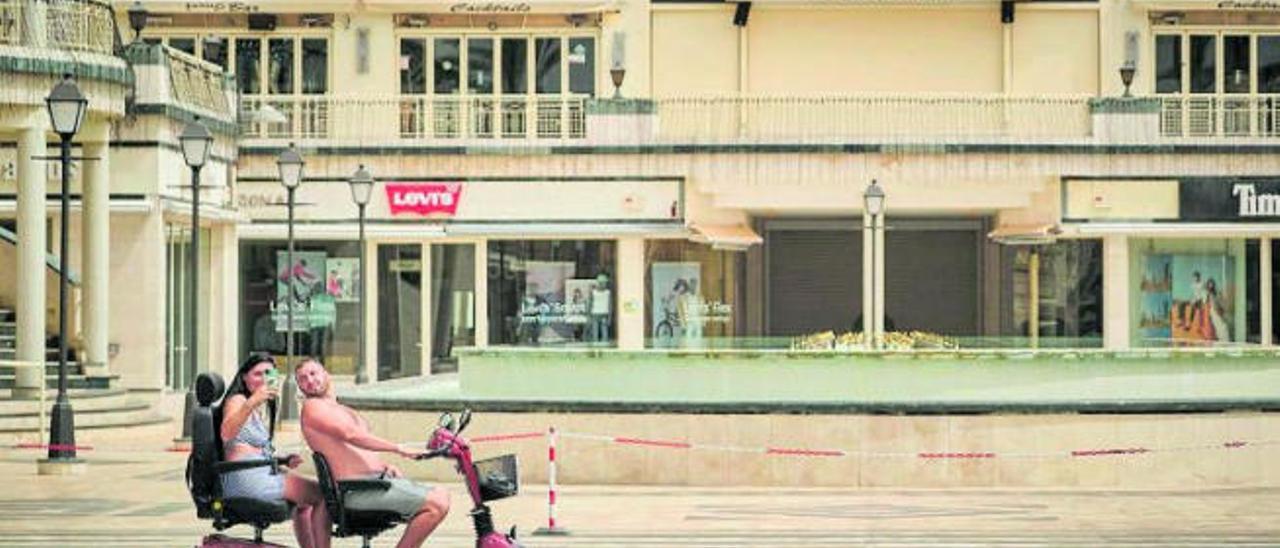 Una pareja de turistas se hace fotos esta semana ante un centro comercial cerrado en el municipio de Arona .