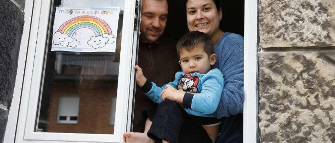 Kiko Montañés y Jenifer Ordiales, con su hijo Enzo, en la ventana de su casa, en La Camocha.