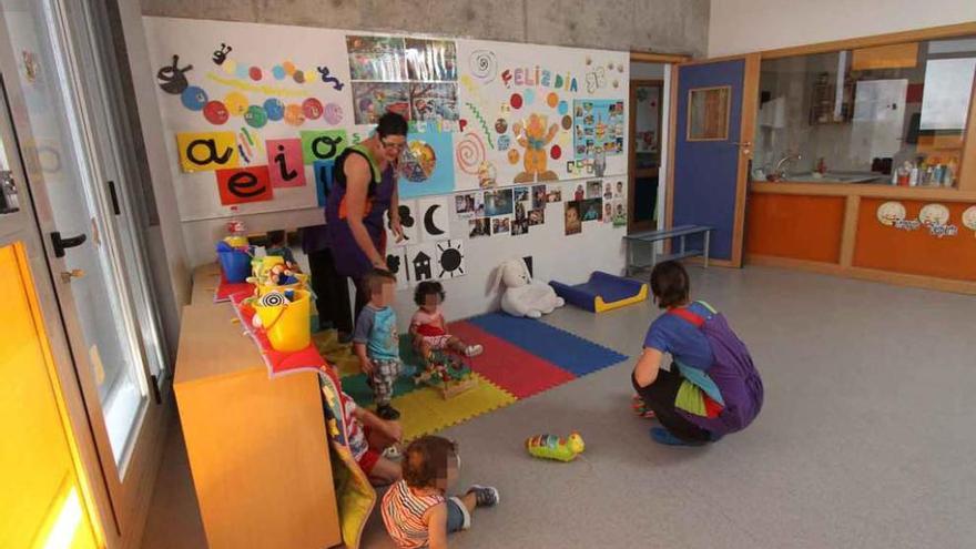 Dos cuidadoras atienden a unos niños en la guardería de La Aldehuela.