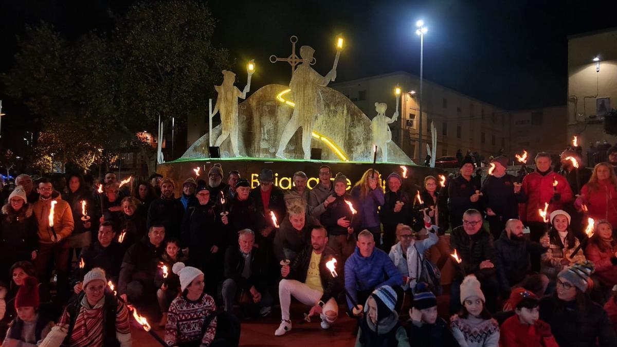 Los antorcheros de Bolón posando con el alcalde de Elda en la escultura que homenajea un festejo único en el mundo.