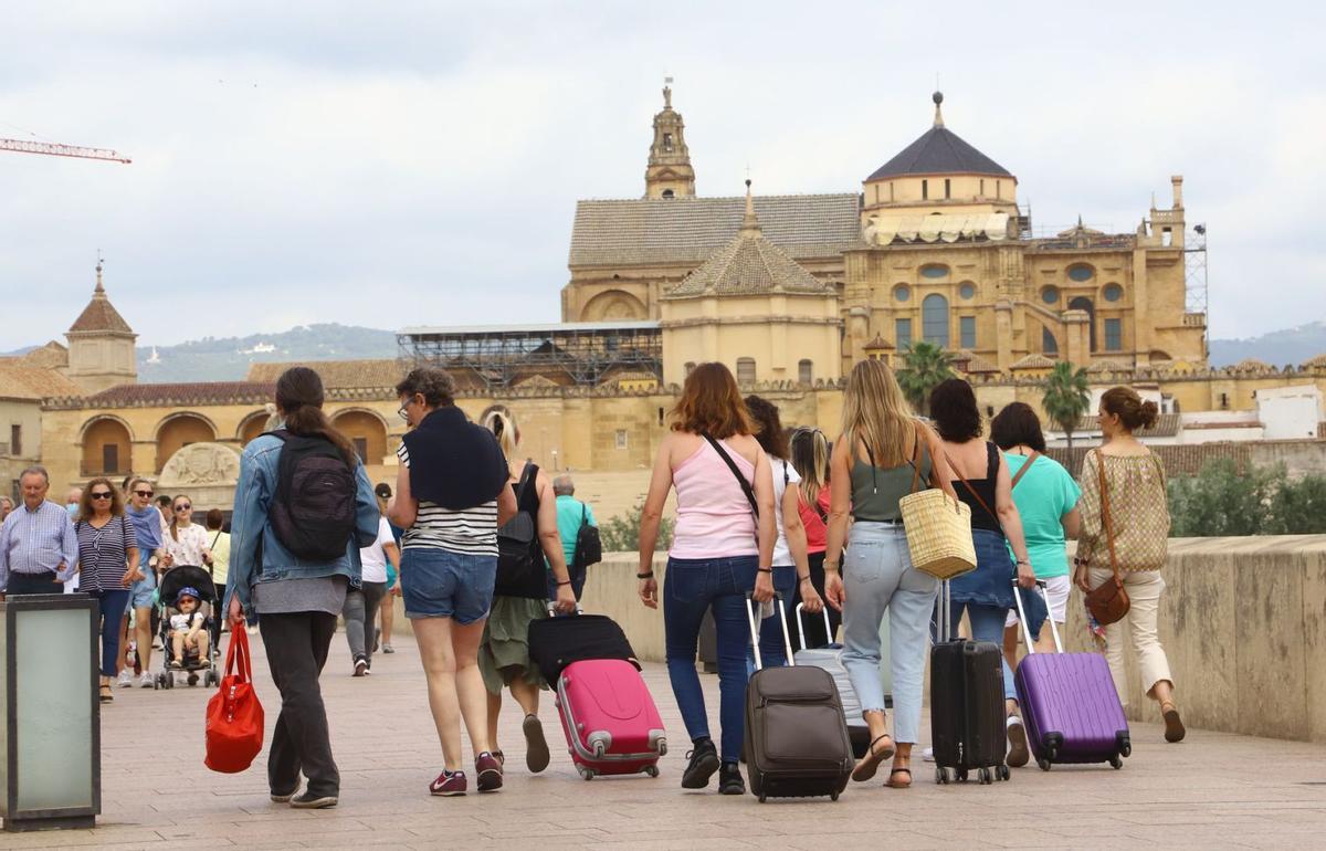 Visitantes cargados con sus maletas cruzan el Puente Romano. | FRANCISCO GONZÁLEZ