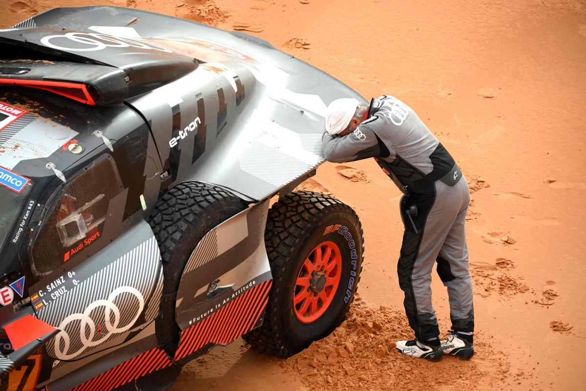 El piloto español Carlos Sainz, reacciona junto a su automóvil después de un accidente durante la Etapa 9 del rally Dakar.