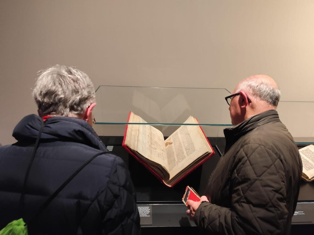 Dos visitants, el dia de la inauguració, contemplant la Bíblia de Rodes.