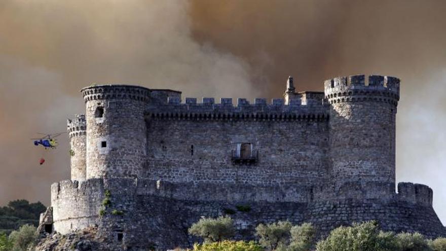 El castillo de Mombeltran, con el humo al fondo provocado por el incendio declarado al sur de la provincia de Ávila.