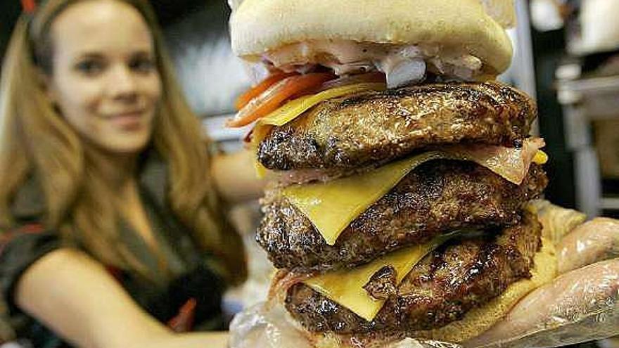 Una camarera muestra una gran hamburguesa. / matt york