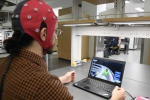 Uno de los científicos usa una gorra repleta de electrodos que está conectada a un ordenador. Los electrodos recopilan datos midiendo señales eléctricas del cerebro y el decodificador interpreta esa información, traduciéndola en acciones de juego.