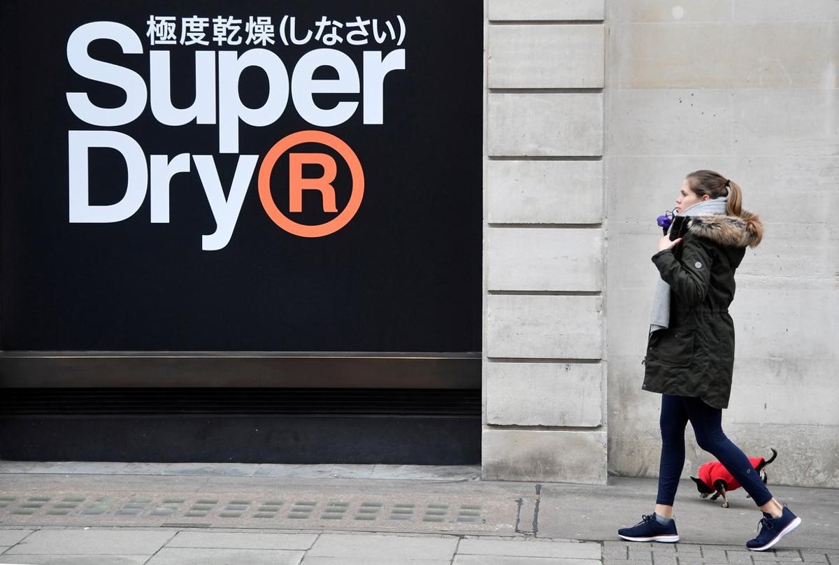 FILE PHOTO: A woman walks past a window display at a Superdry store in London, Britain, March 1, 2019. REUTERS/Toby Melville/File Photo