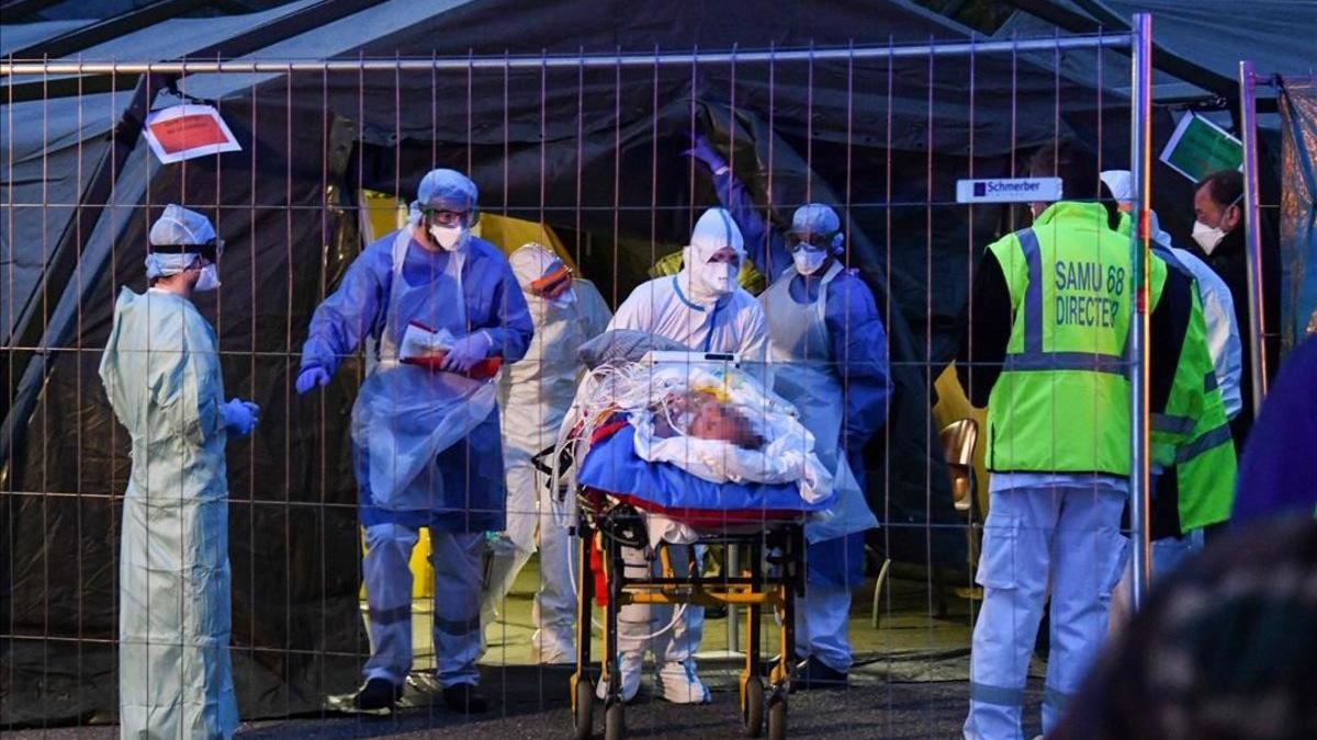 Traslado de un paciente con coronavirus desde un hospital militar a un ambulancia en Mulhouse, Francia