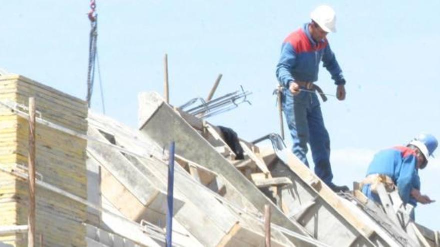 Dos trabajadores de la construcción, sobre un tejado en obras.