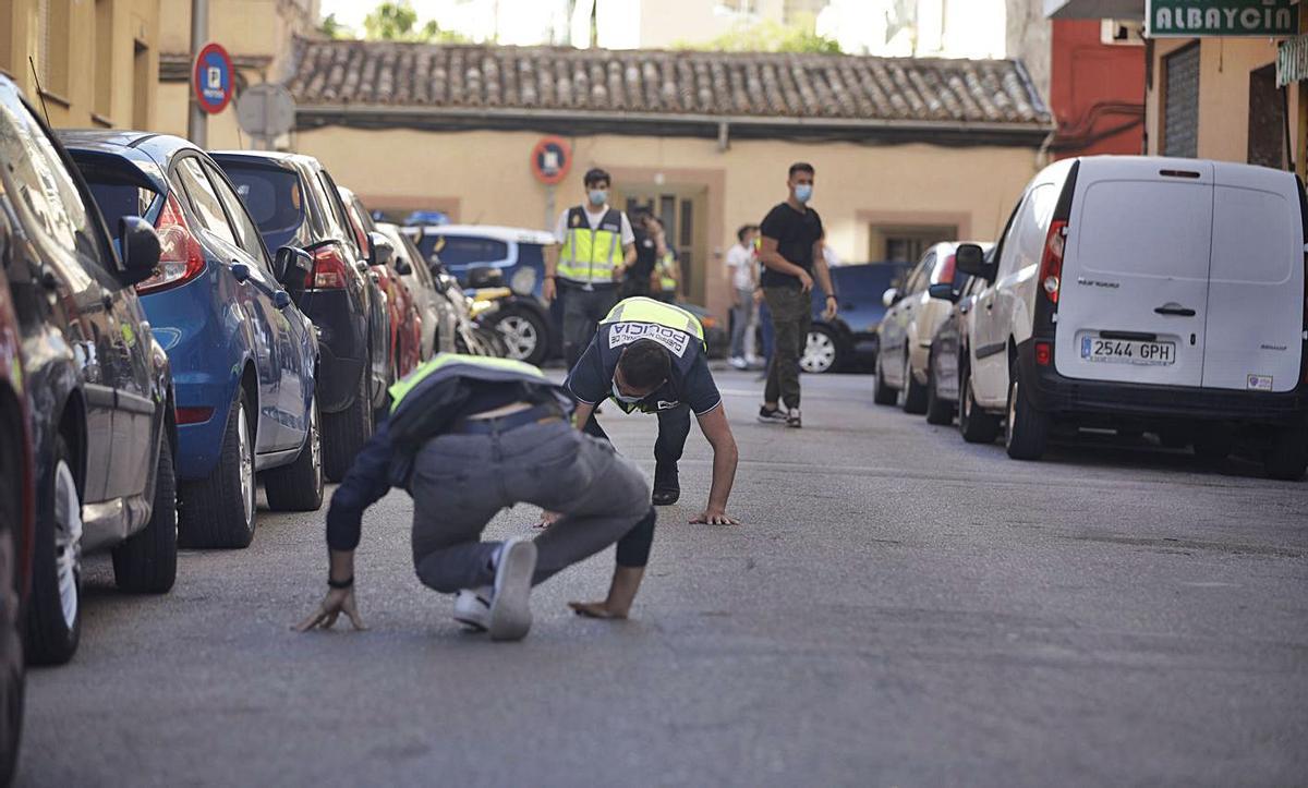 Dos agentes de Policía buscan  casquillos de bala  en la calle Sant Fulgenci. | GUILLEM BOSCH