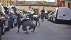 Dos agentes de Policía buscan  casquillos de bala  en la calle Sant Fulgenci. | GUILLEM BOSCH