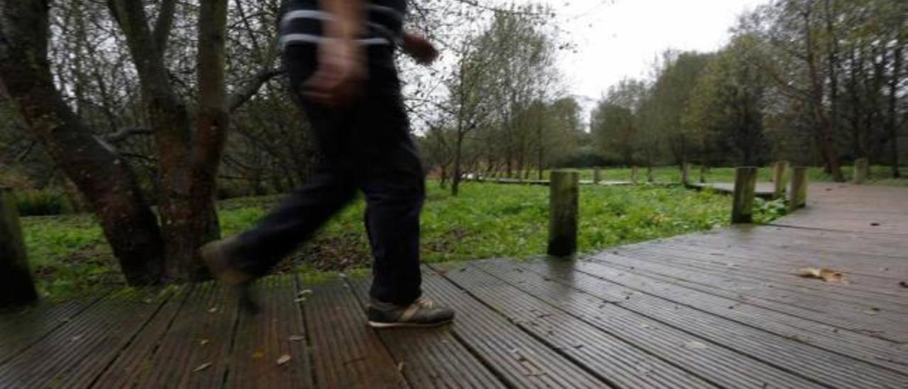 Un hombre camina por el suelo de madera de la senda fluvial.