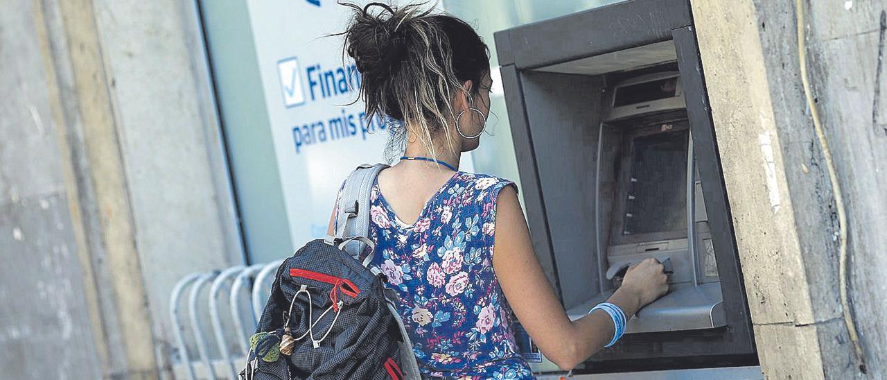 Una mujer opera en un cajero automático de una entidad bancaria.