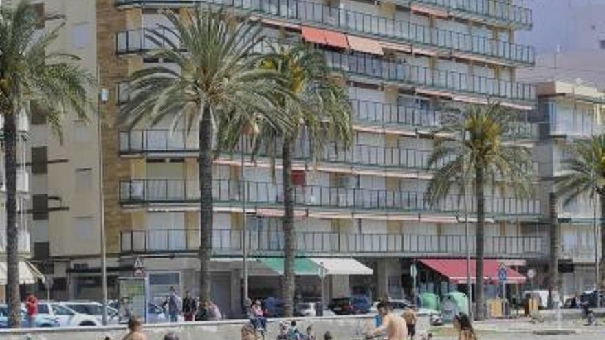 Turistas jugando en la playa con varios apartamentos y viviendas de fondo en Santa Pola.
